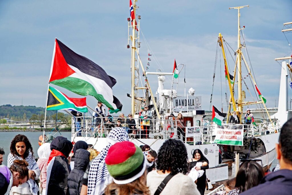 Crowds of supporters greet the boat Handala in Cork (Cobh) harbour. Palestinian and other flags flying.